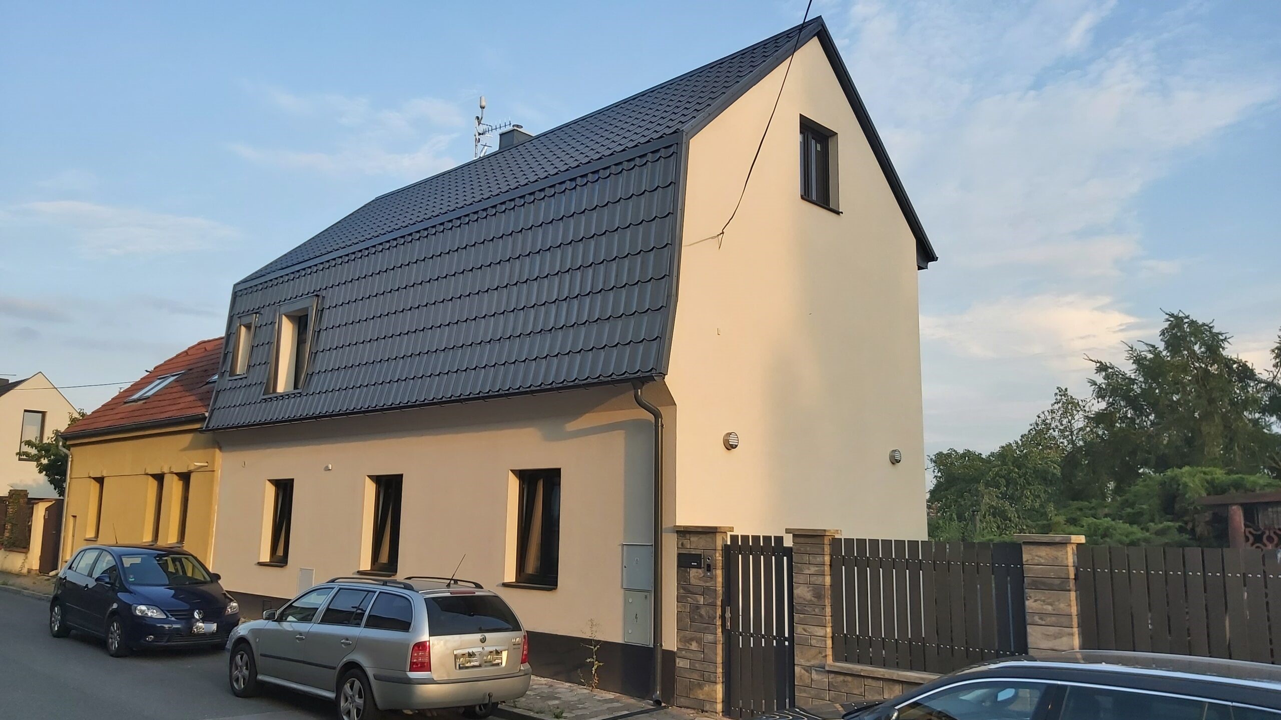 Nově zrekonstruovaný dům s bílou fasádou a tmavou střechou.